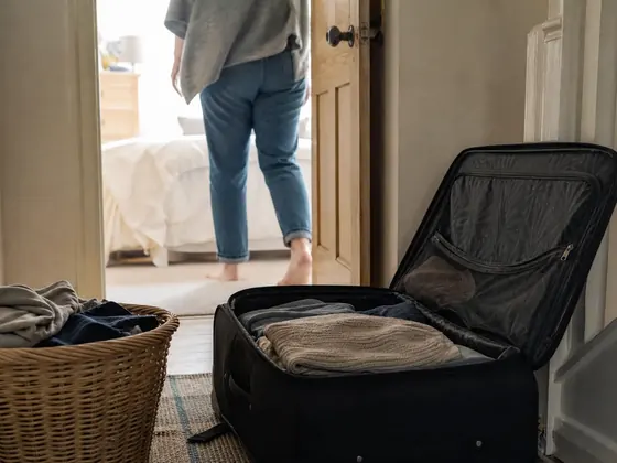 unpacked suitcase, laundry basket, hallway