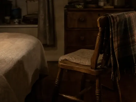 chair beside a cot, dim room