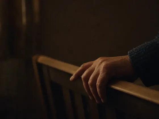 hand on a cot rail in the dark