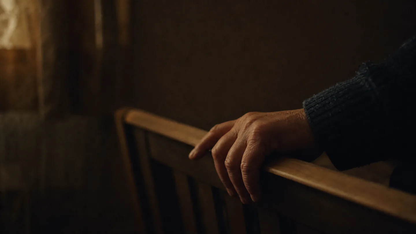 hand on a cot rail in the dark