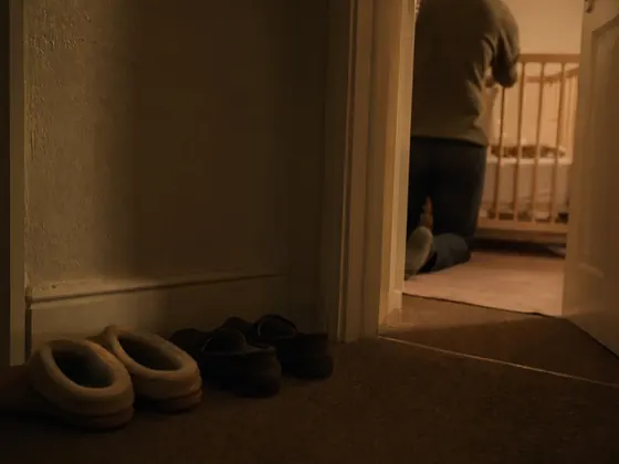 two adults in a hallway, nursery door behind