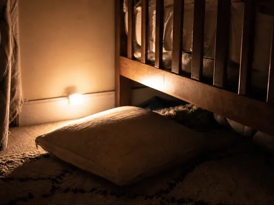 floor cushion beside a cot, night light